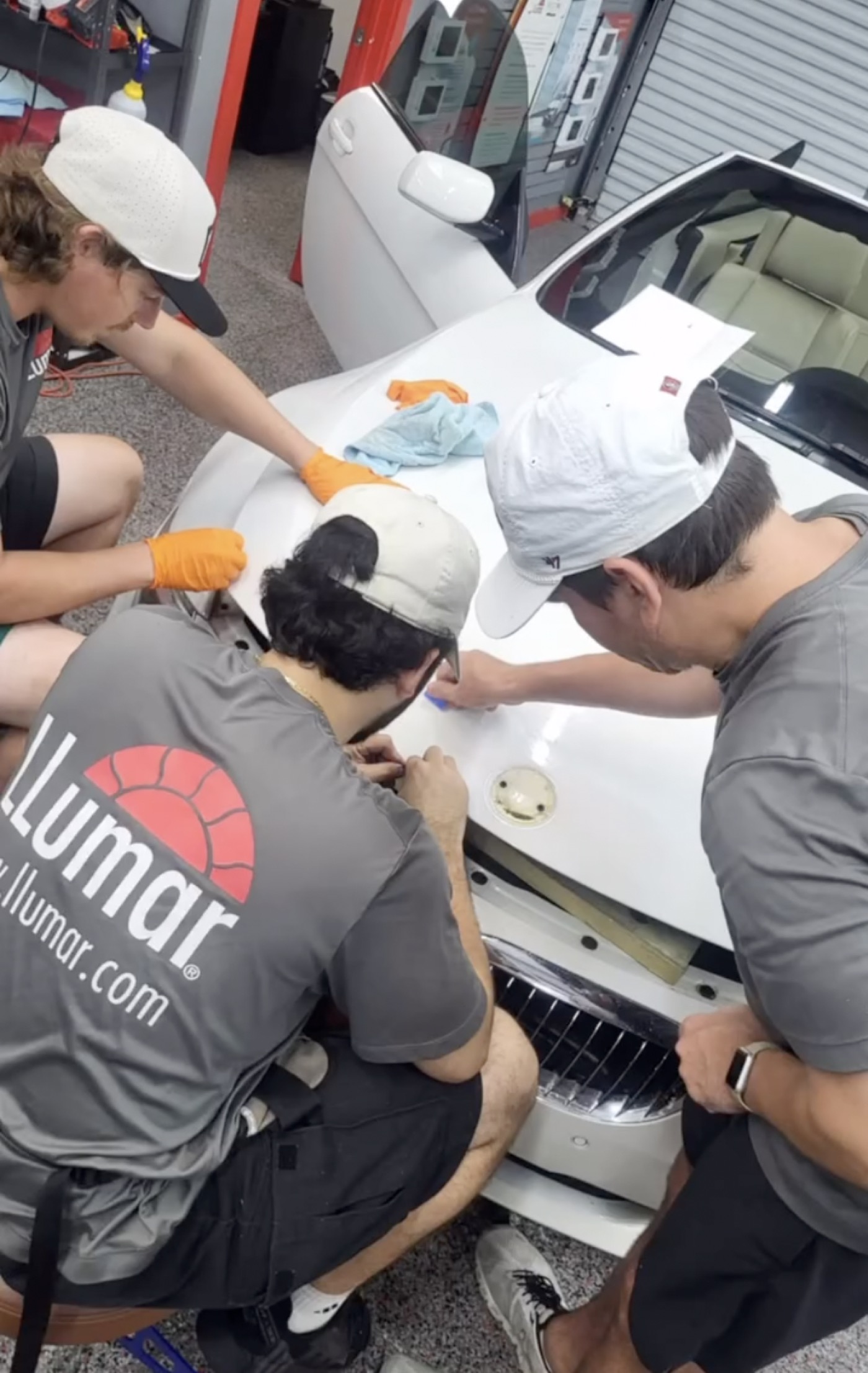 Exzact installers applying LLumar film to a vehicle in the shop